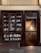 A storefront with glass windows displaying books on shelves. The book covers are of various colors and designs. There is a glass door on the right side, illuminated by warm light from inside, revealing a staircase.