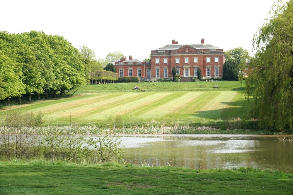 brown concrete building near green grass field and body of water during daytime