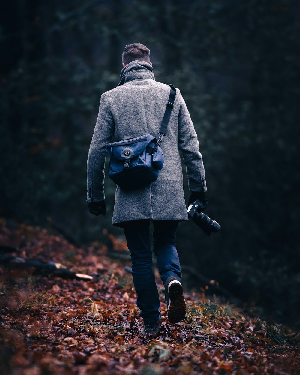 person in gray hoodie and blue denim jeans walking on forest during daytime