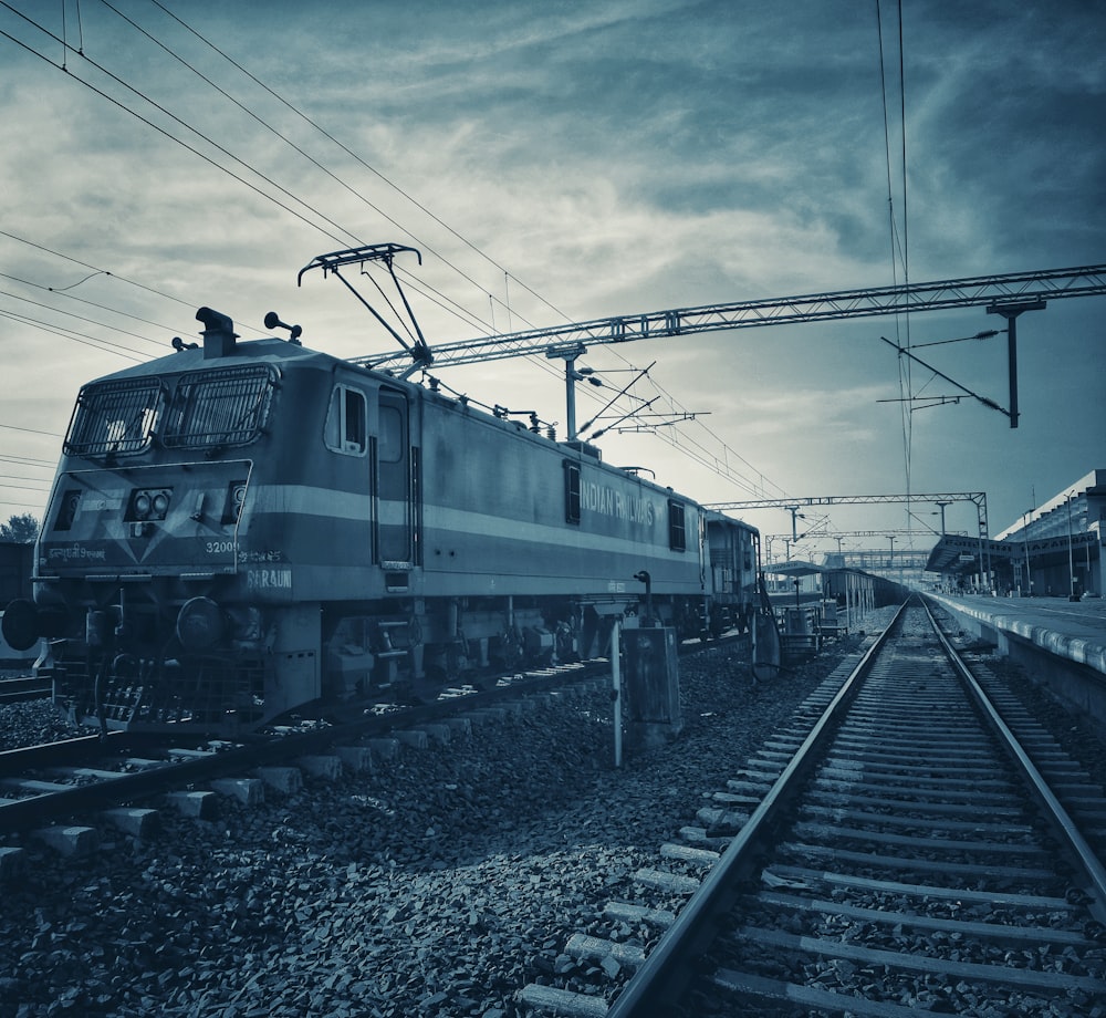 Grüner Zug auf Bahngleisen unter bewölktem Himmel