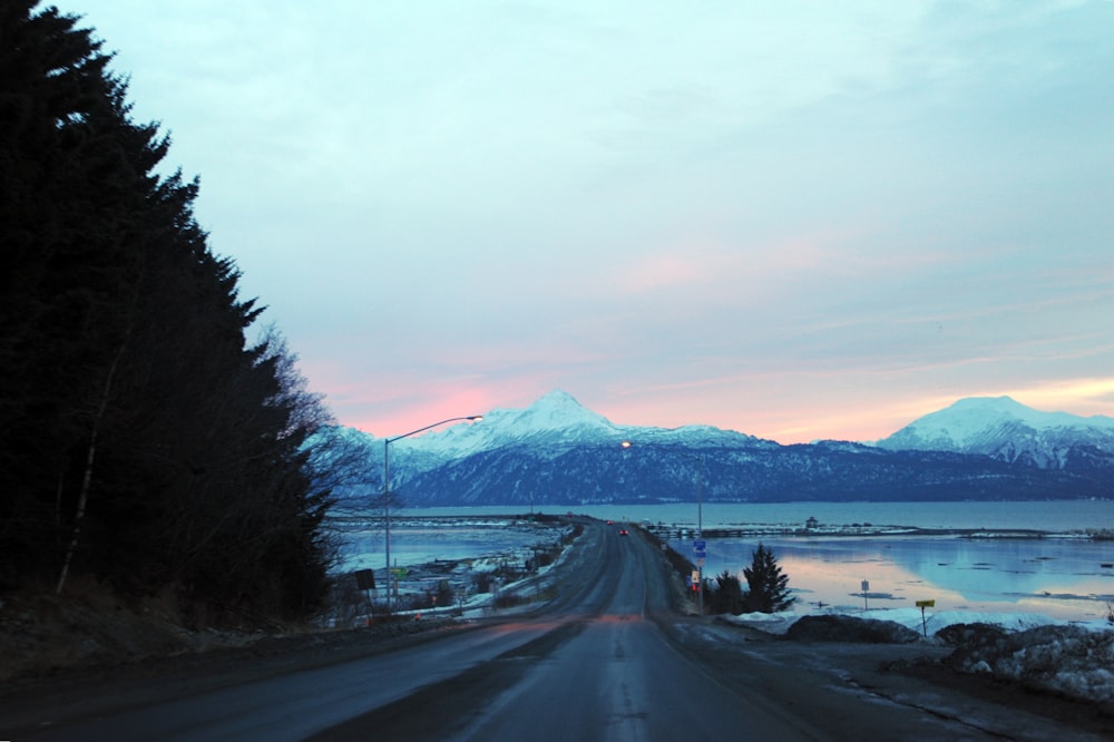 black asphalt road near snow covered mountain during daytime