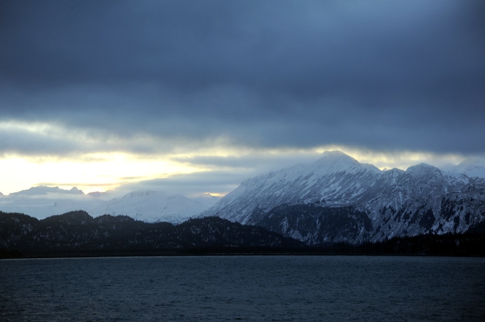 snow covered mountain near body of water during daytime