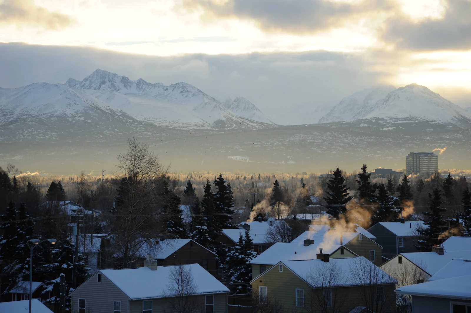 Anchorage homes in winter with chimney smoke and the Chugach Mountains