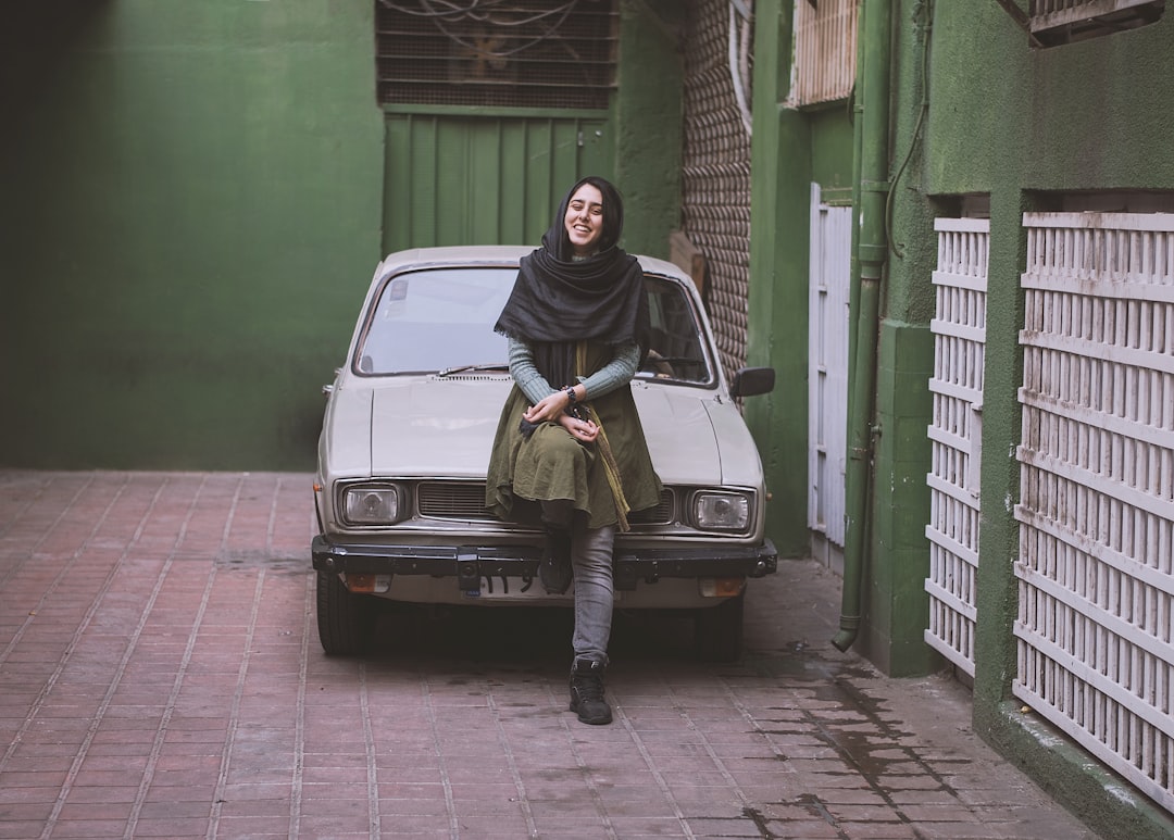 woman in black hijab and yellow long sleeve dress sitting on white car
