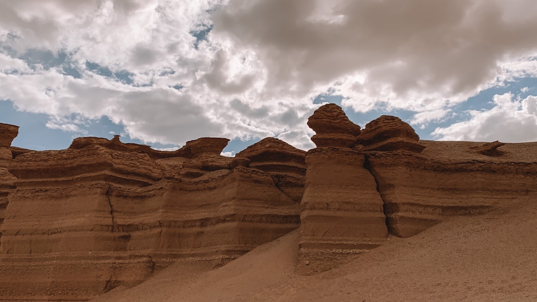 brown rock formation under white clouds during daytime