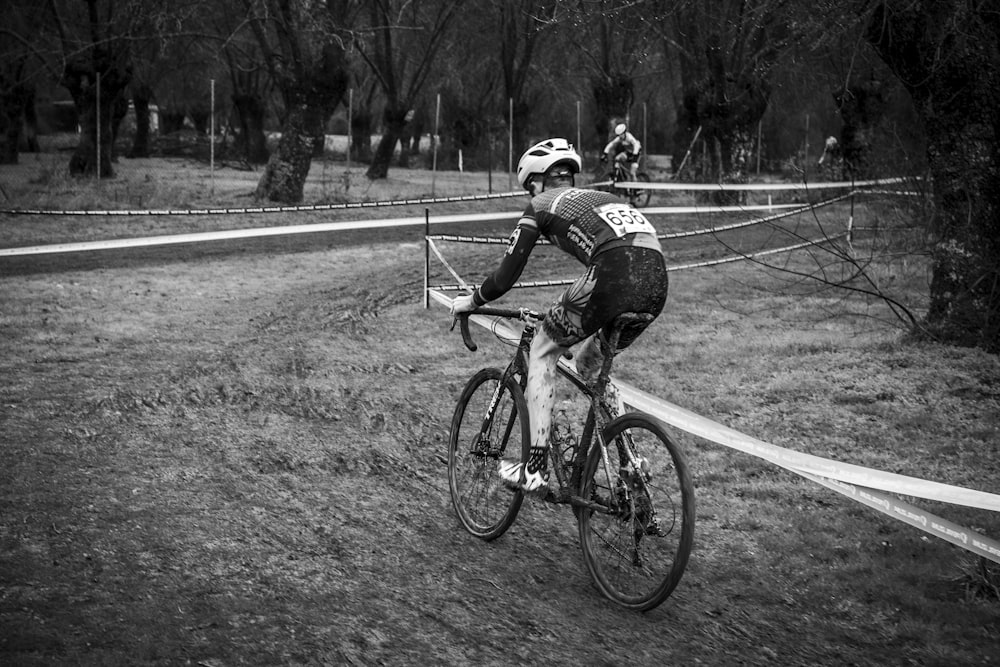 grayscale photo of man riding bicycle