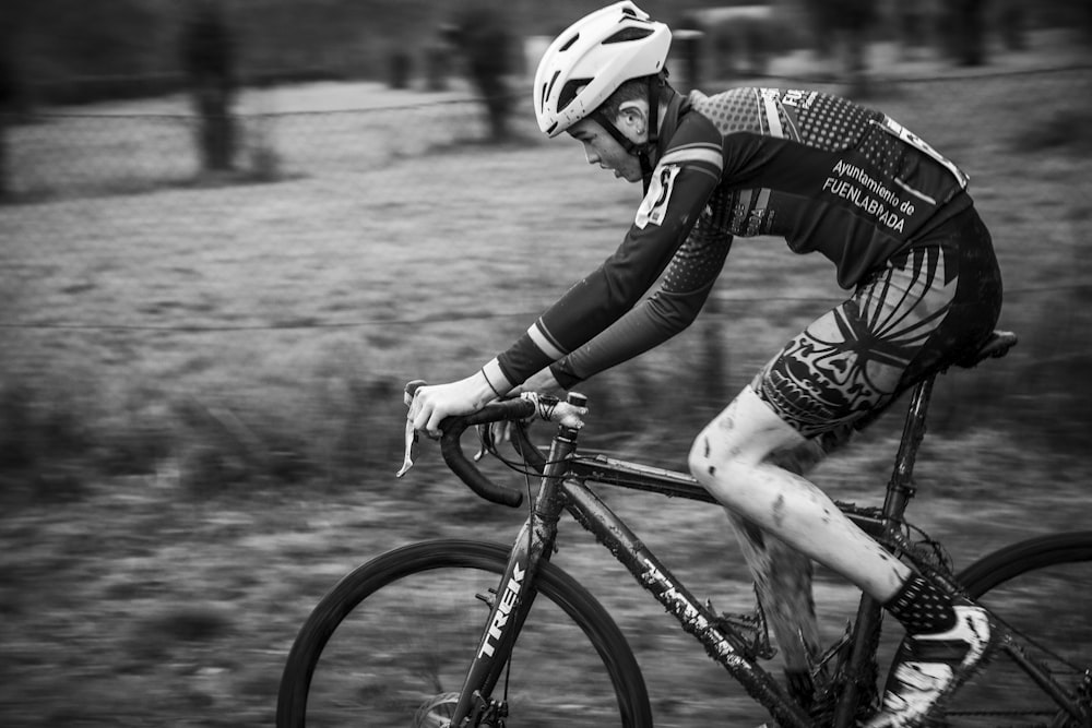 grayscale photo of man riding on bicycle