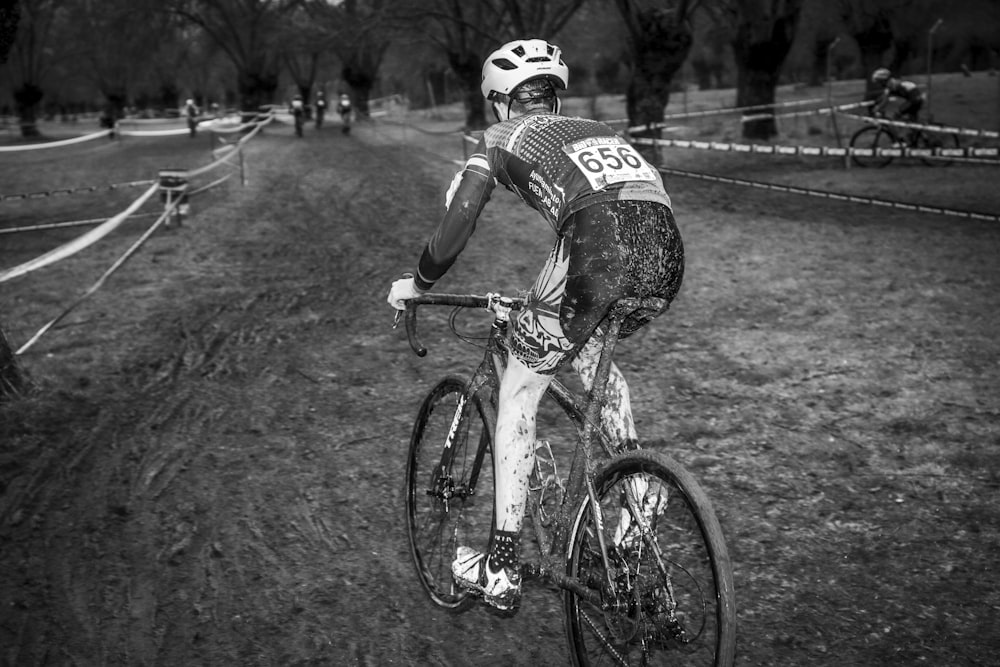 grayscale photo of man riding bicycle