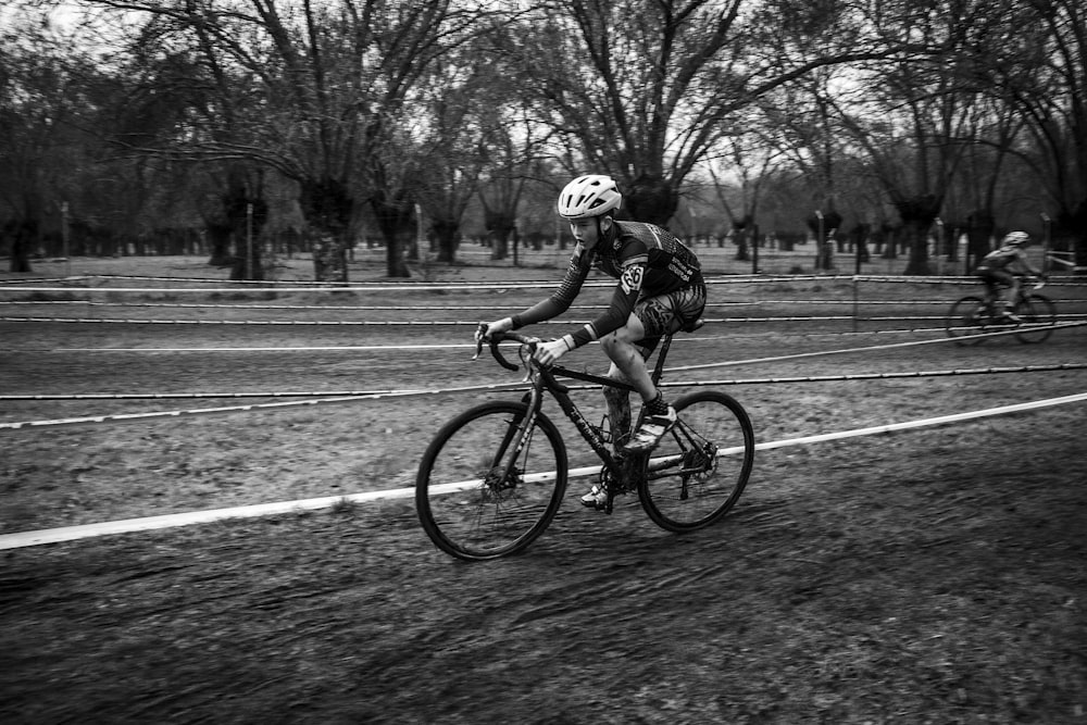 grayscale photo of man riding bicycle on road