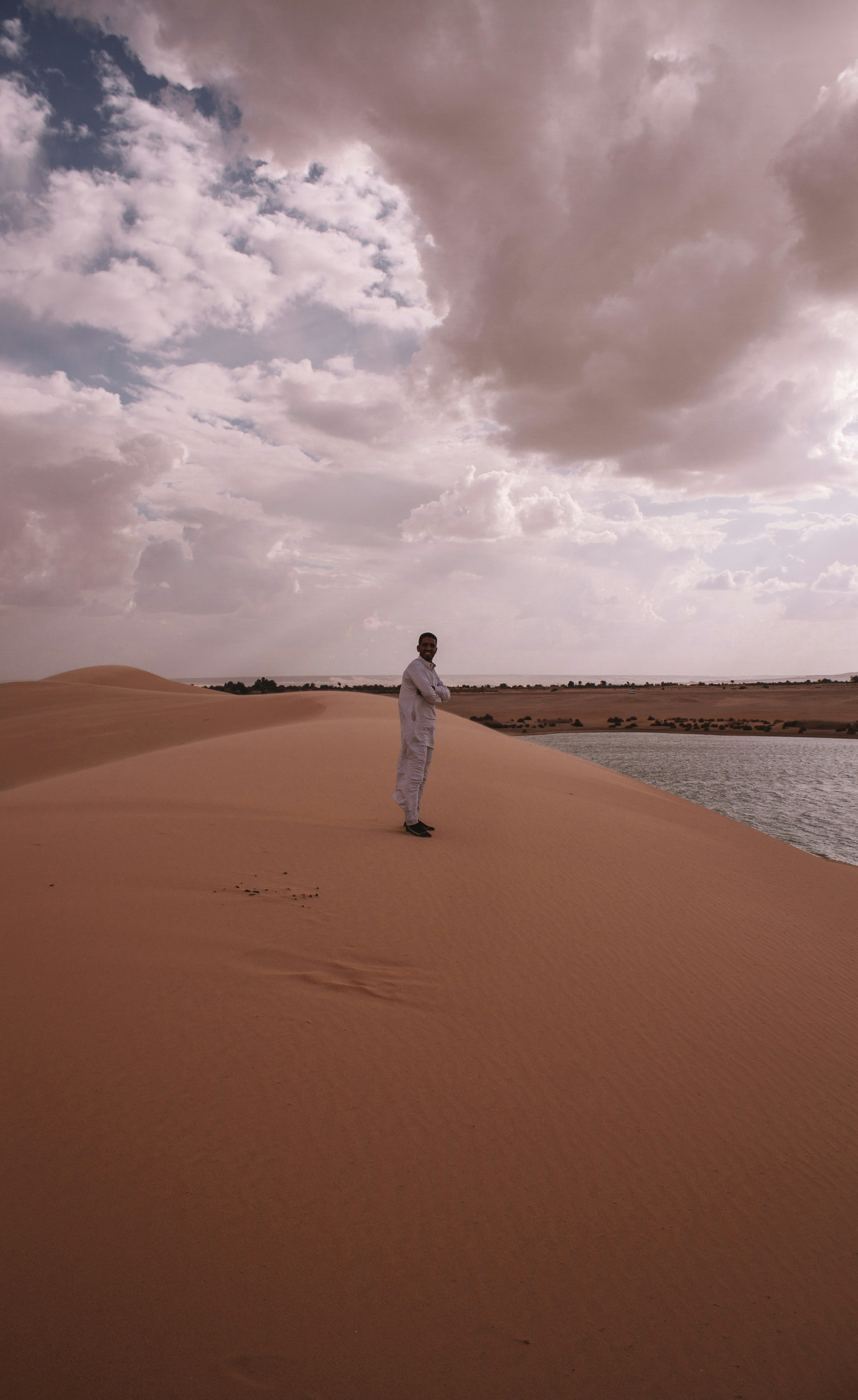 woman in white dress walking on sand during daytime