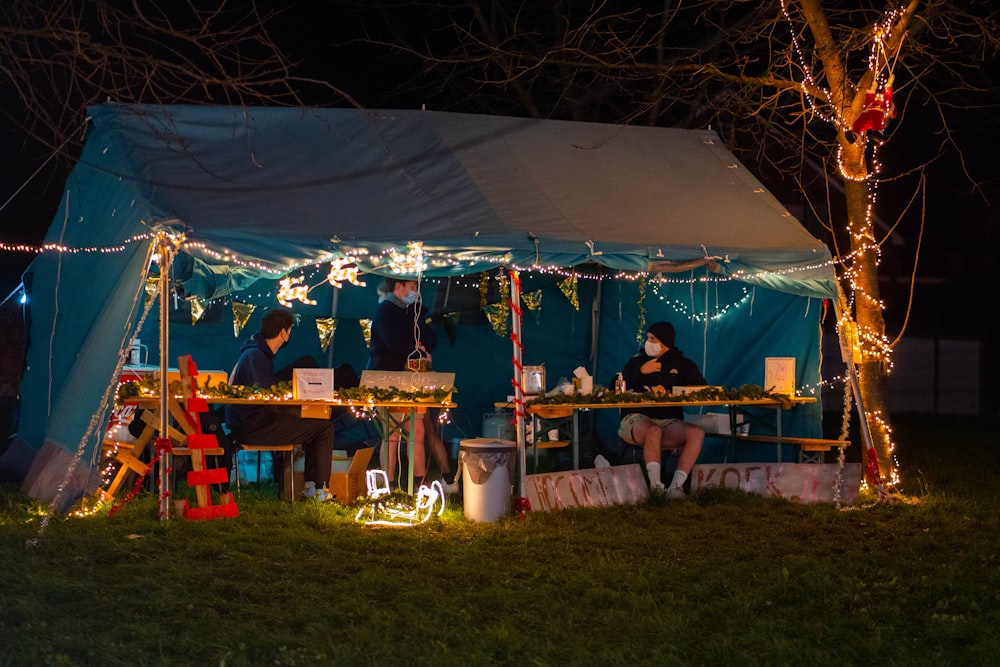 people sitting on chair under blue canopy tent during daytime