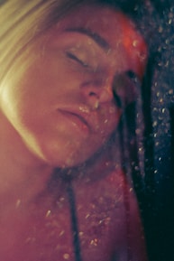 Close-up of a calm face illuminated by soft cosmic light, eyes gently closed.