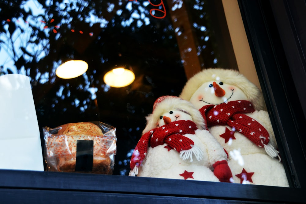 white snowman plush toy on glass window