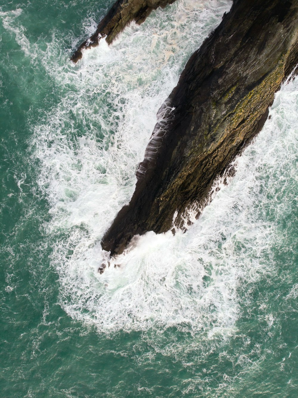 brown rock formation beside body of water during daytime