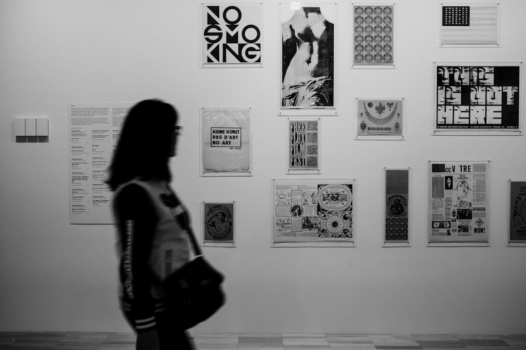 grayscale photo of woman in long sleeve shirt standing in front of wall with wall mounted