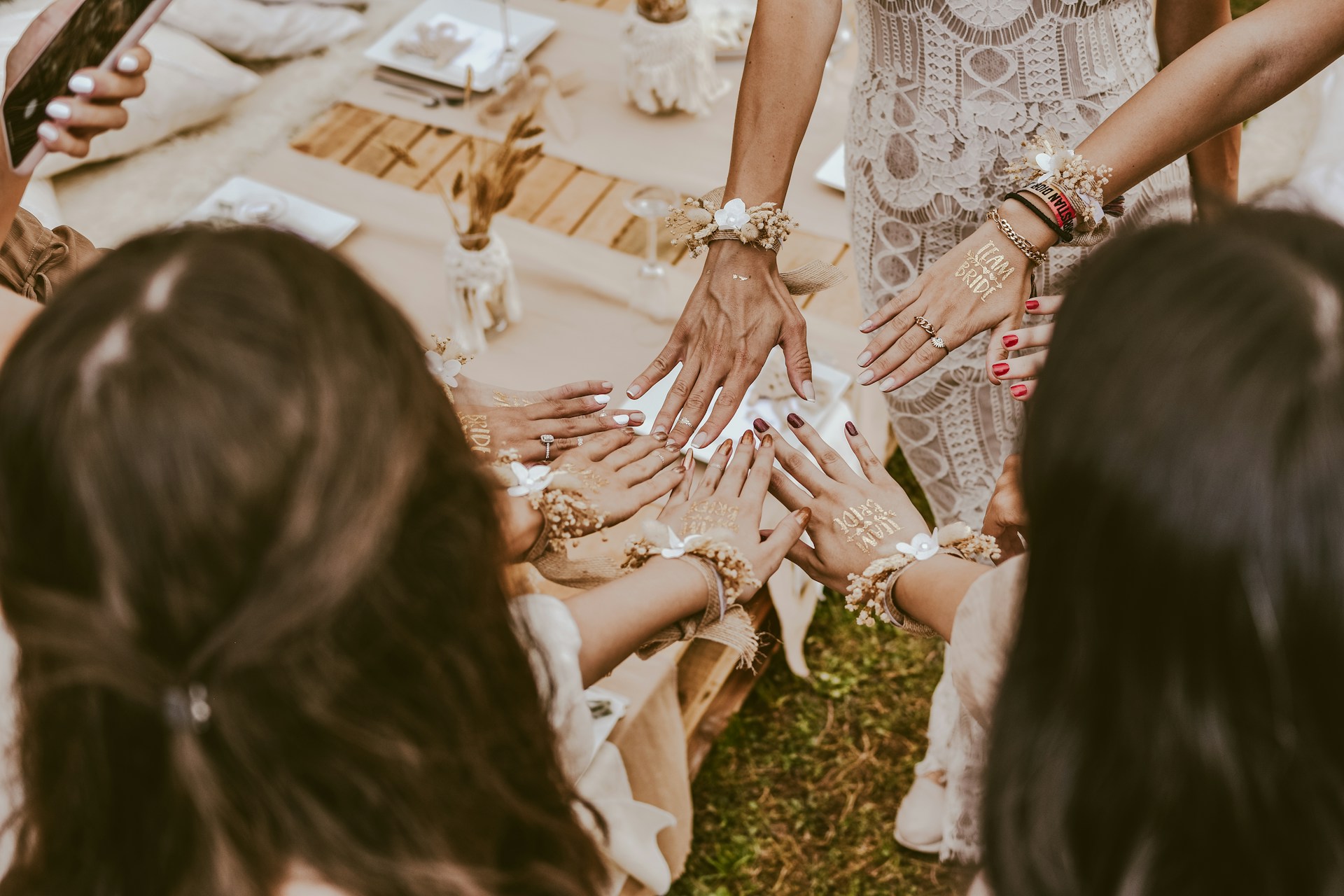 A joyful group of girls laughing together, their hands decorated with colorful mendhi designs celebrating a festive occasion.