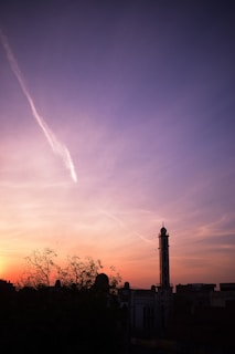 A peaceful sunset over a desert landscape with a silhouette of a minaret.