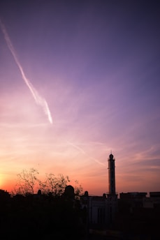 A serene sunset over a traditional Islamic cityscape with minarets silhouetted against the colorful sky.