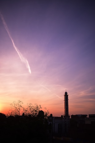 A peaceful sunset over a desert landscape with a silhouette of a minaret.