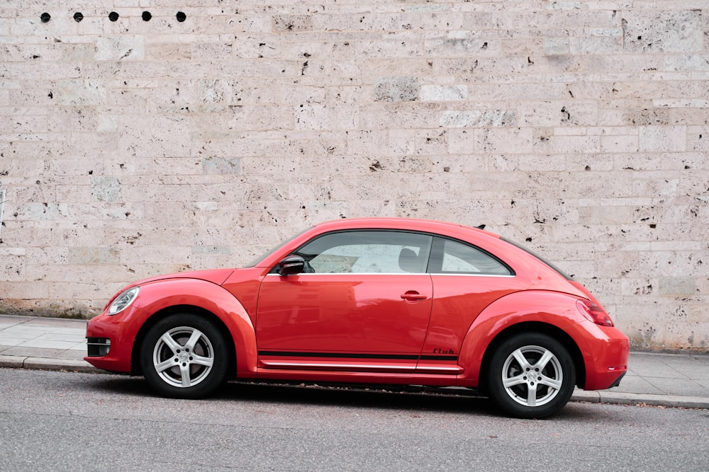 red coupe parked beside white wall