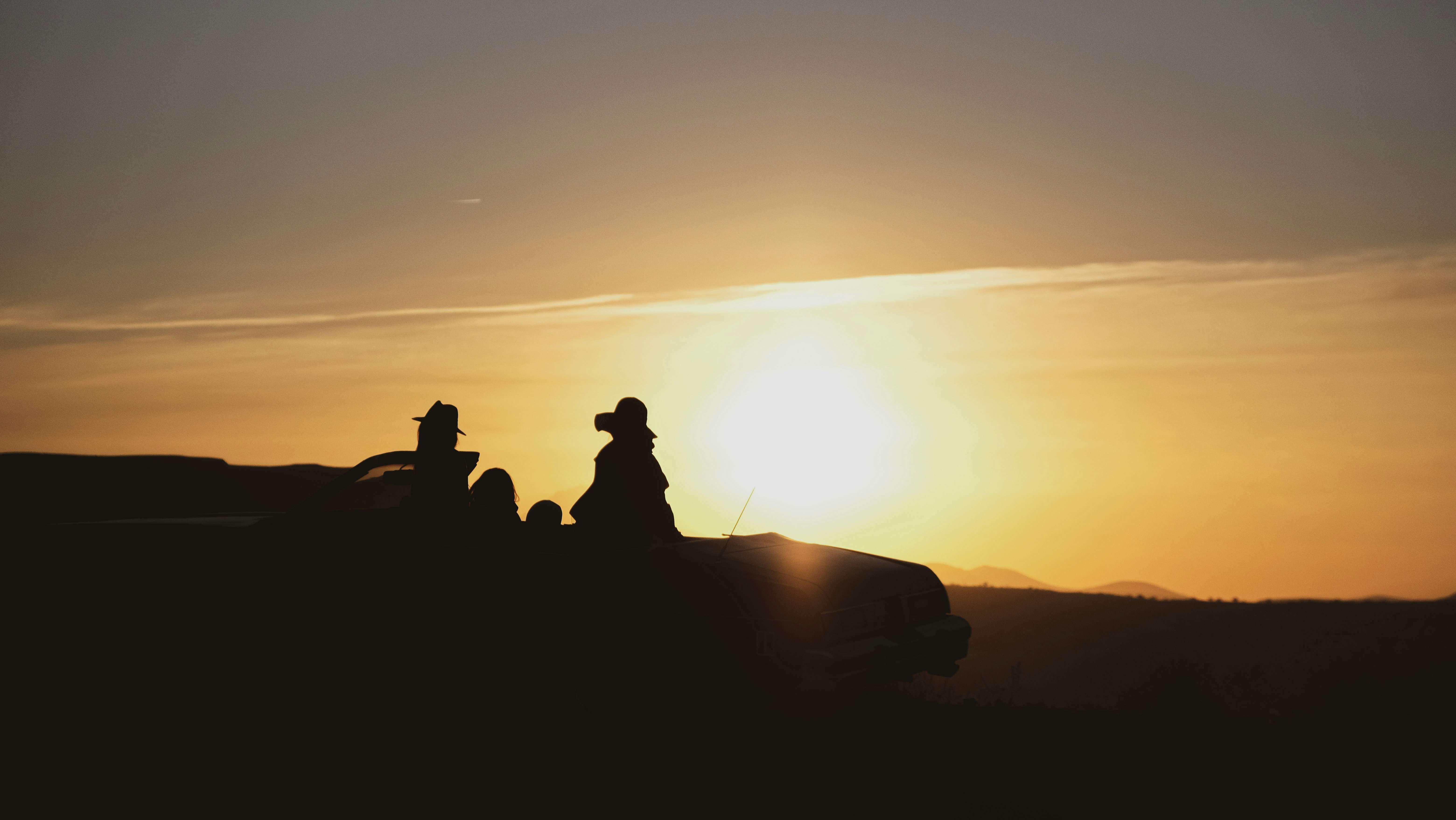 silhouette of people sitting on ground during sunset