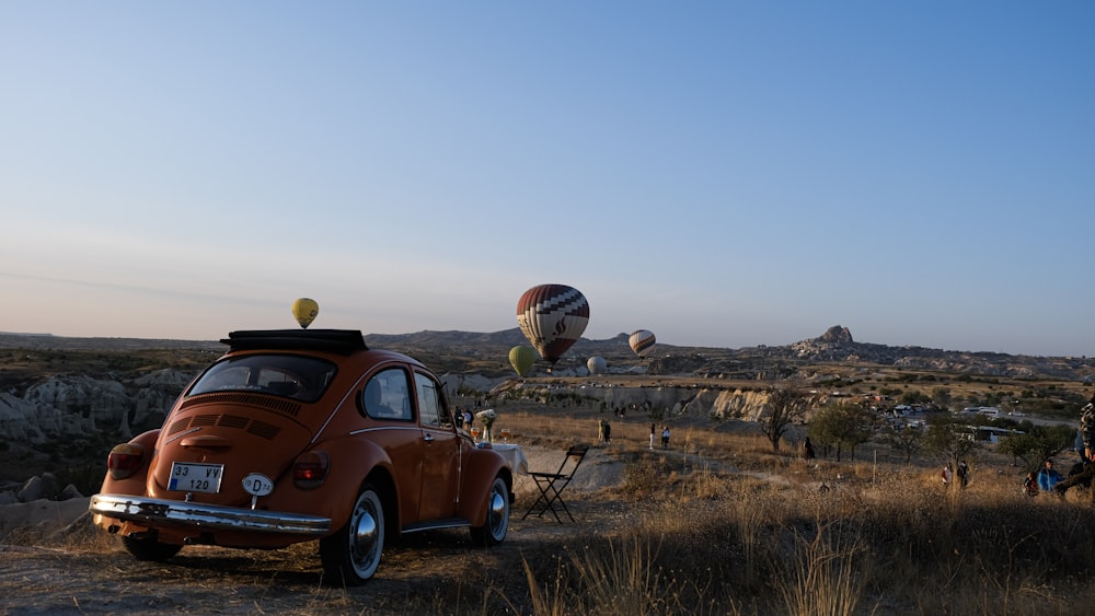 red volkswagen beetle on dirt road during daytime