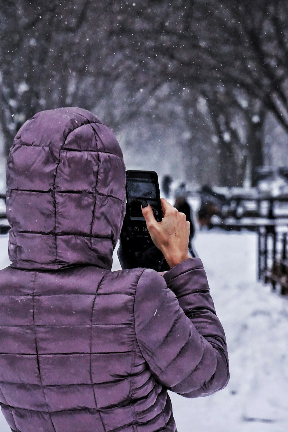 person in purple hoodie holding black smartphone