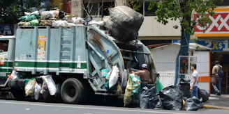 Truck collecting bulky waste from a commercial site with workers loading items carefully.