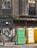 A weathered urban scene featuring a worn building facade with cracked windows, adorned with faded graffiti and rusted metal elements. Three portable toilets in green, yellow, and white stand in front of a graffitied and shuttered storefront.