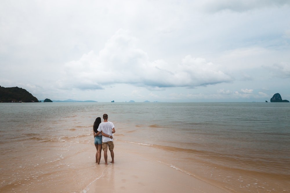 homem e mulher que caminham na praia durante o dia