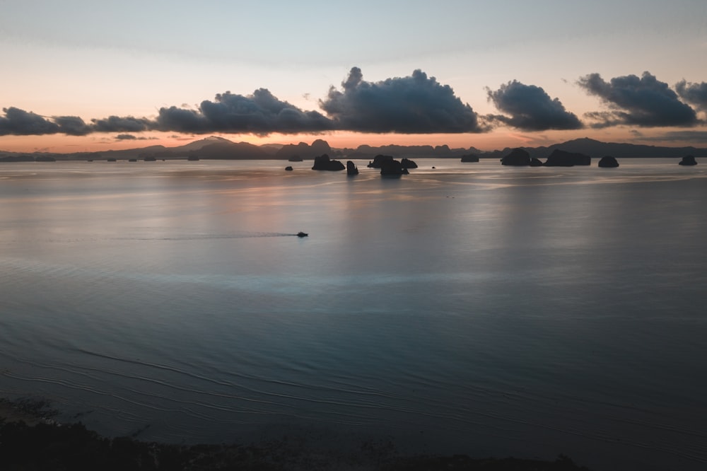 body of water under cloudy sky during sunset