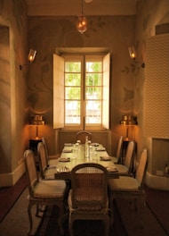 A beautifully set dining table with natural wood finish, surrounded by cozy chairs in a sunlit room.