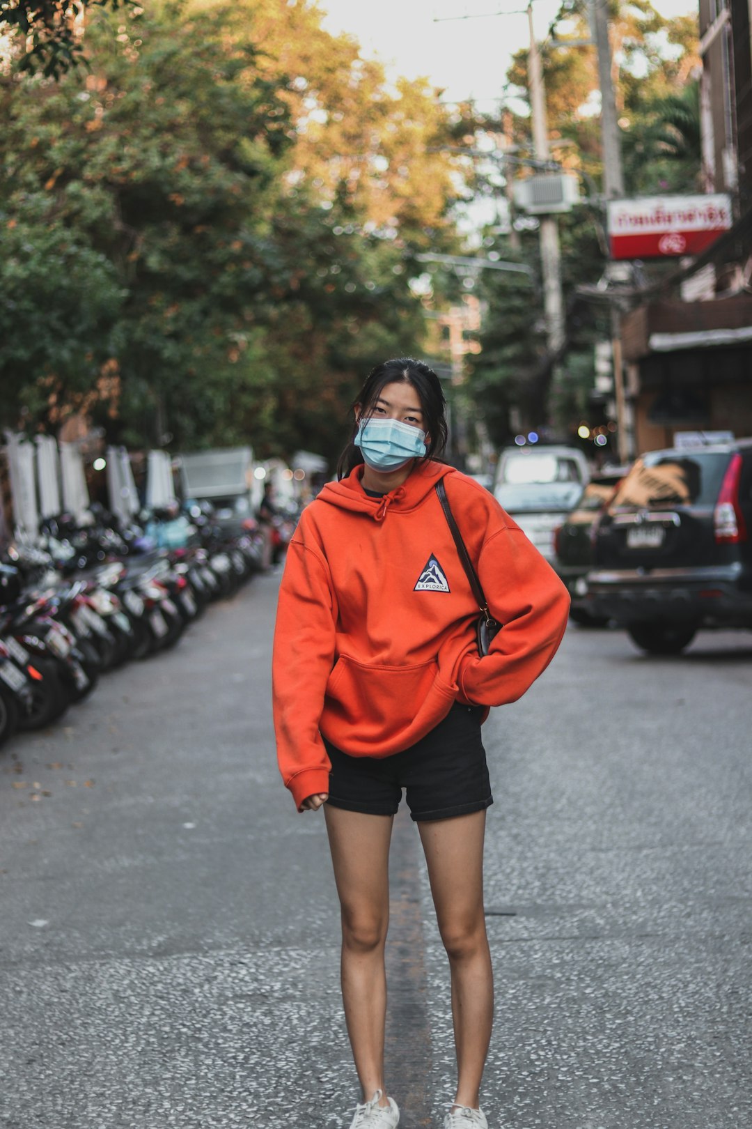 woman in red hoodie standing on road during daytime