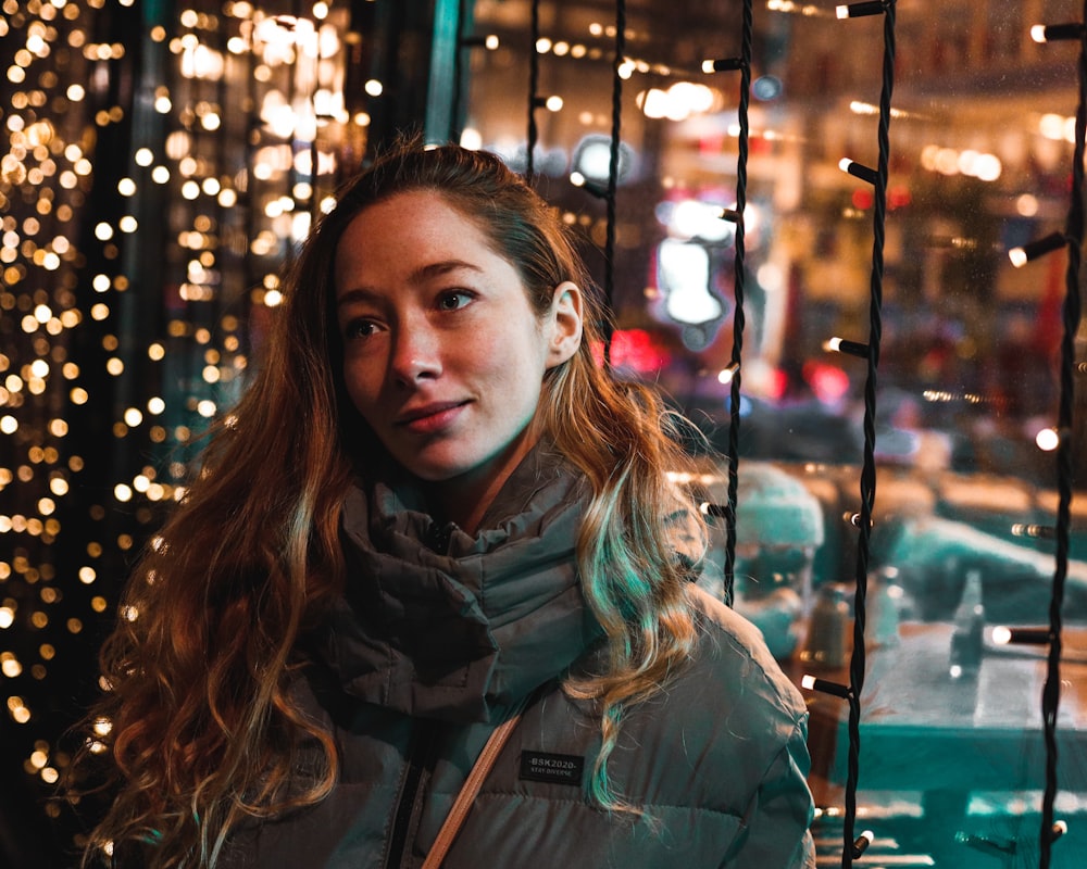 woman in gray jacket standing near glass window