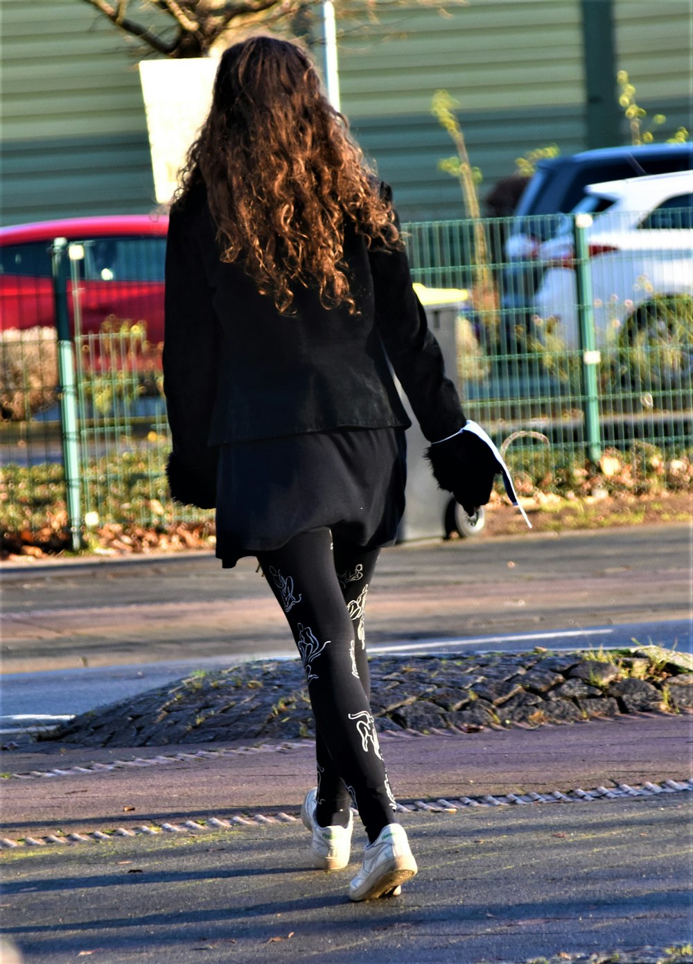 낮 동안 보도를 걷고 있는 검은 코트를 입은 여자