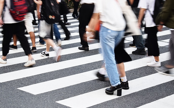 White crosswalk stripes painted across a city street where people walk
