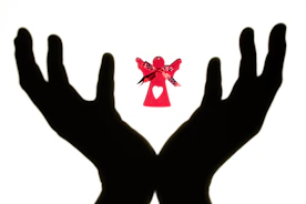 Hands holding glowing angel cards against a peaceful background