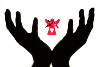 Hands holding glowing angel cards against a peaceful background