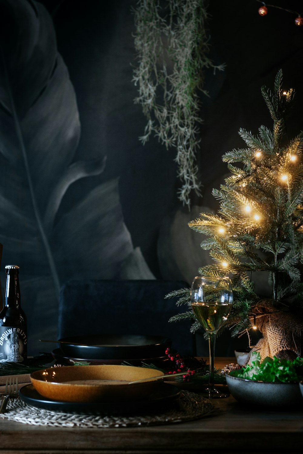 黒いテーブルの近くでストリングライトが点灯した緑のクリスマスツリー