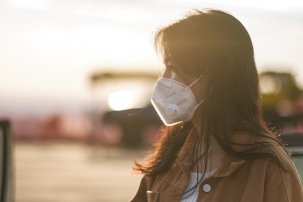 A person comfortably wearing a breathable facemask outdoors with soft natural lighting.