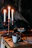 A cozy table setting with flickering candlelight and glowing embers in the background.