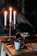 A cozy table setting with flickering candlelight and glowing embers in the background.