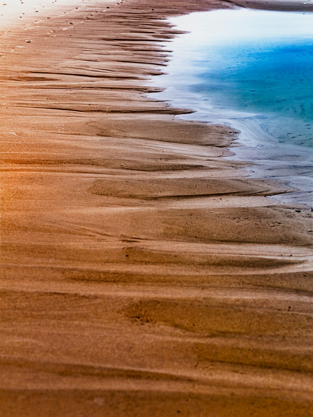 brown sand near body of water during daytime