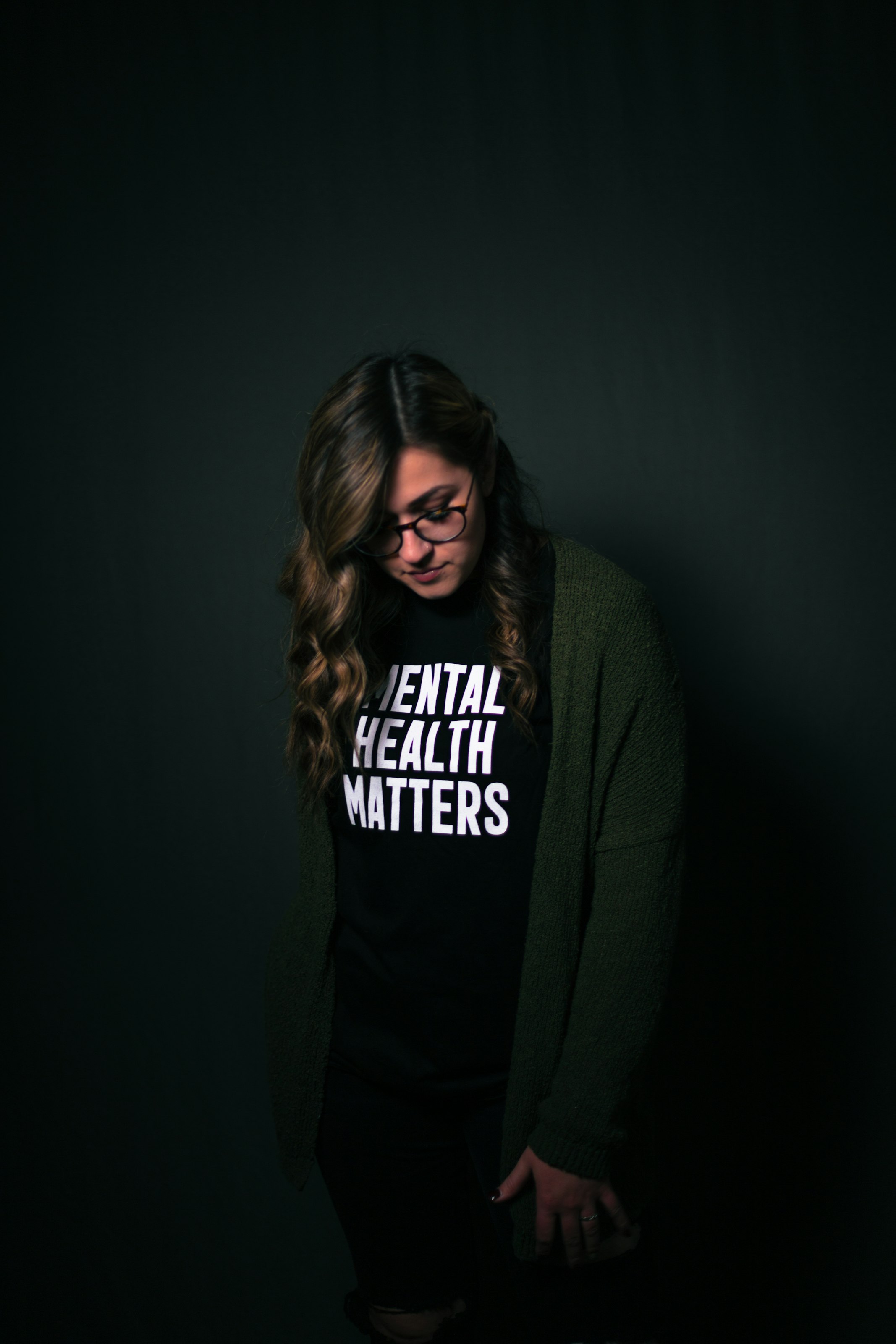 women looking down wearing a black shirt with white text "mental health matters"