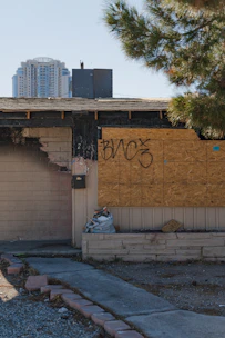 Boarded-up window of a fire-damaged building with emergency signage in Brooklyn.