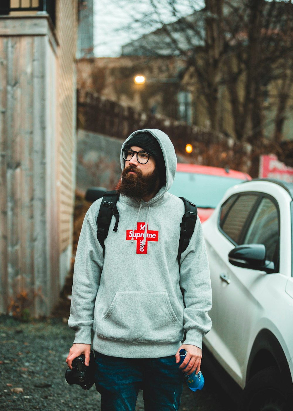 man in gray hoodie standing beside white car during daytime