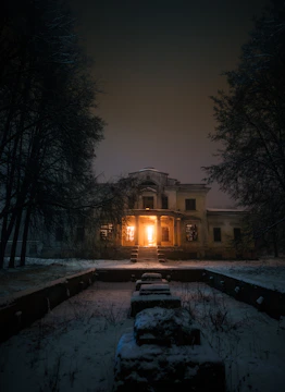 An old, abandoned mansion with flickering candlelight in the windows.