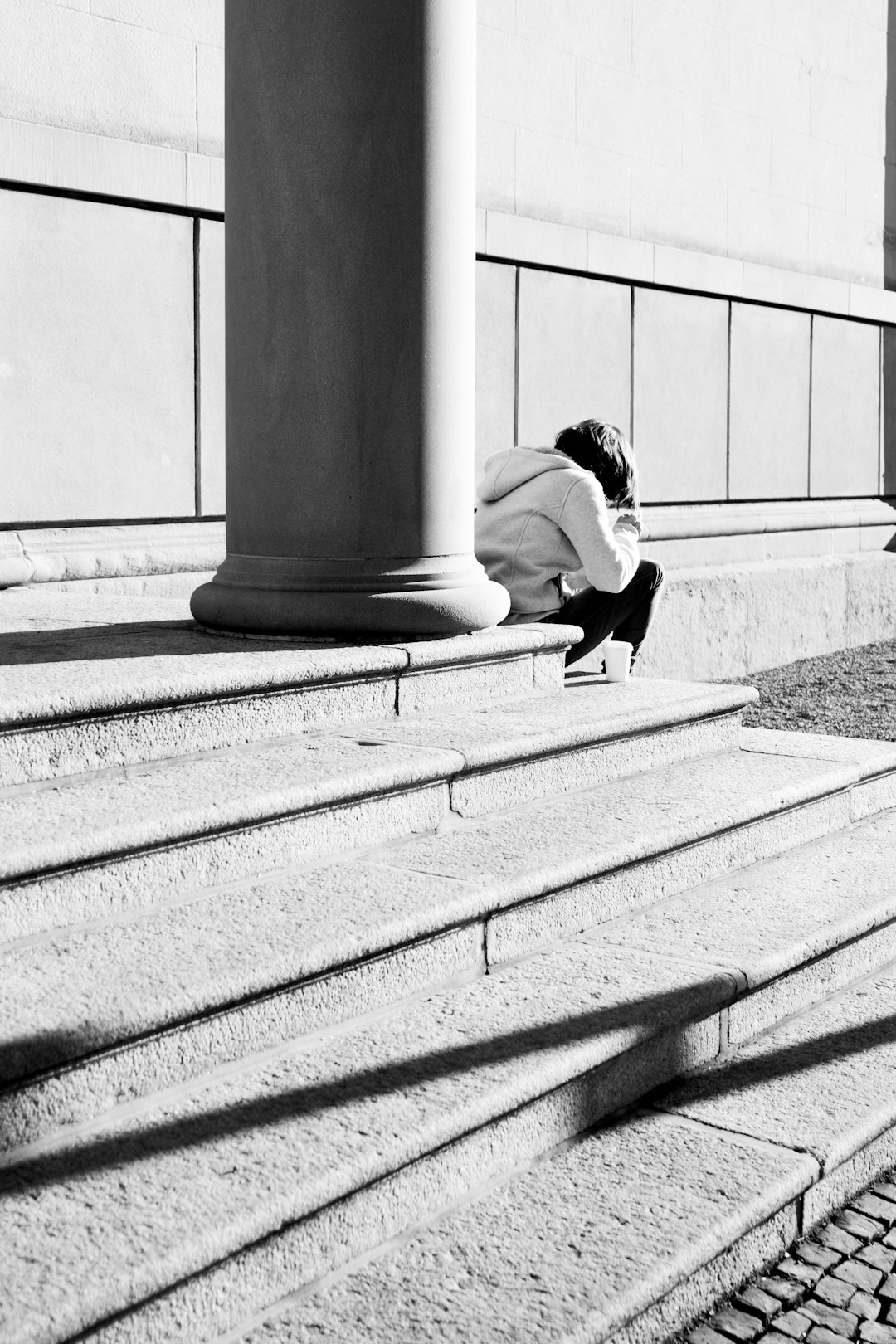 grayscale photo of woman sitting on concrete bench