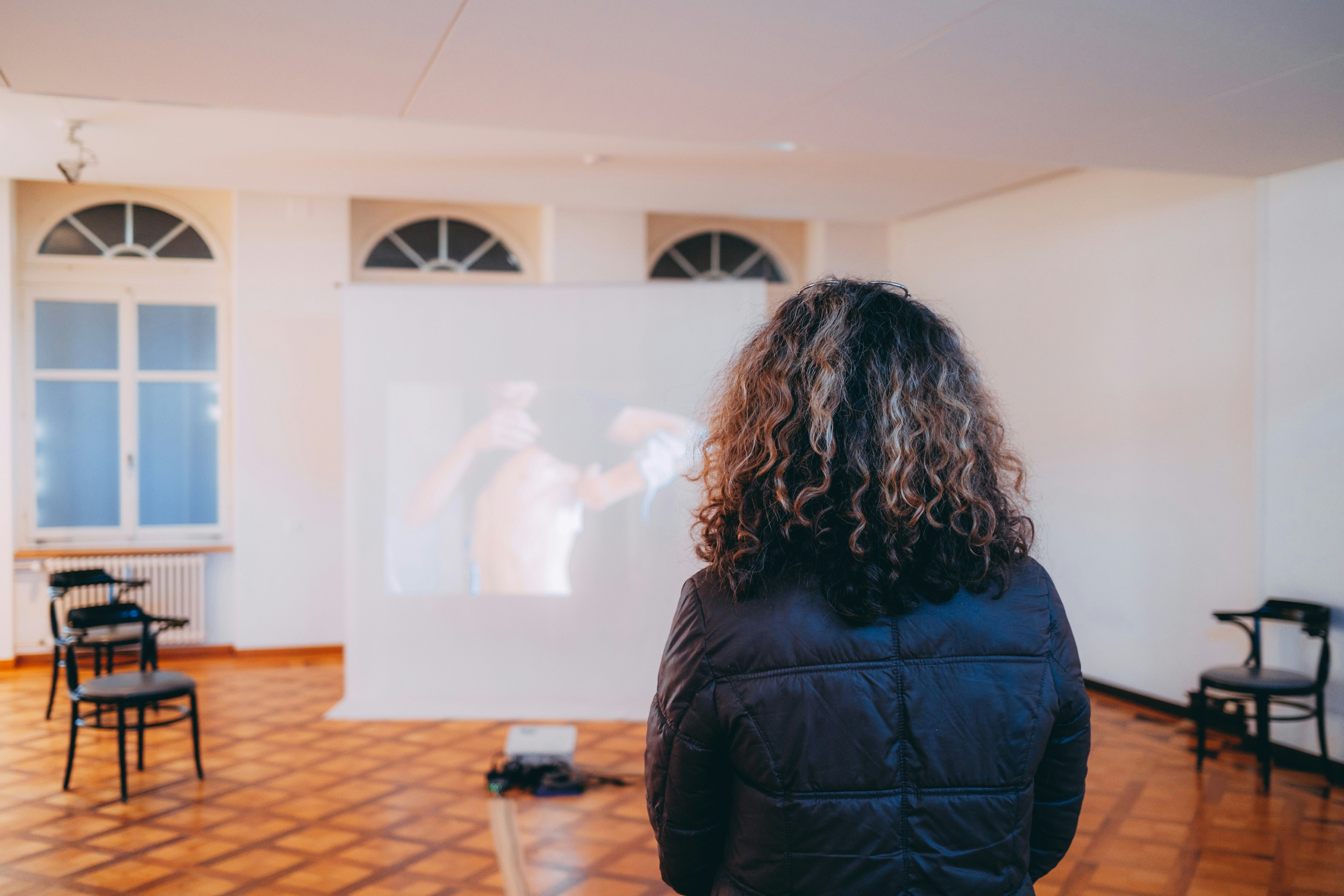 woman in black jacket standing in front of white projector screen
