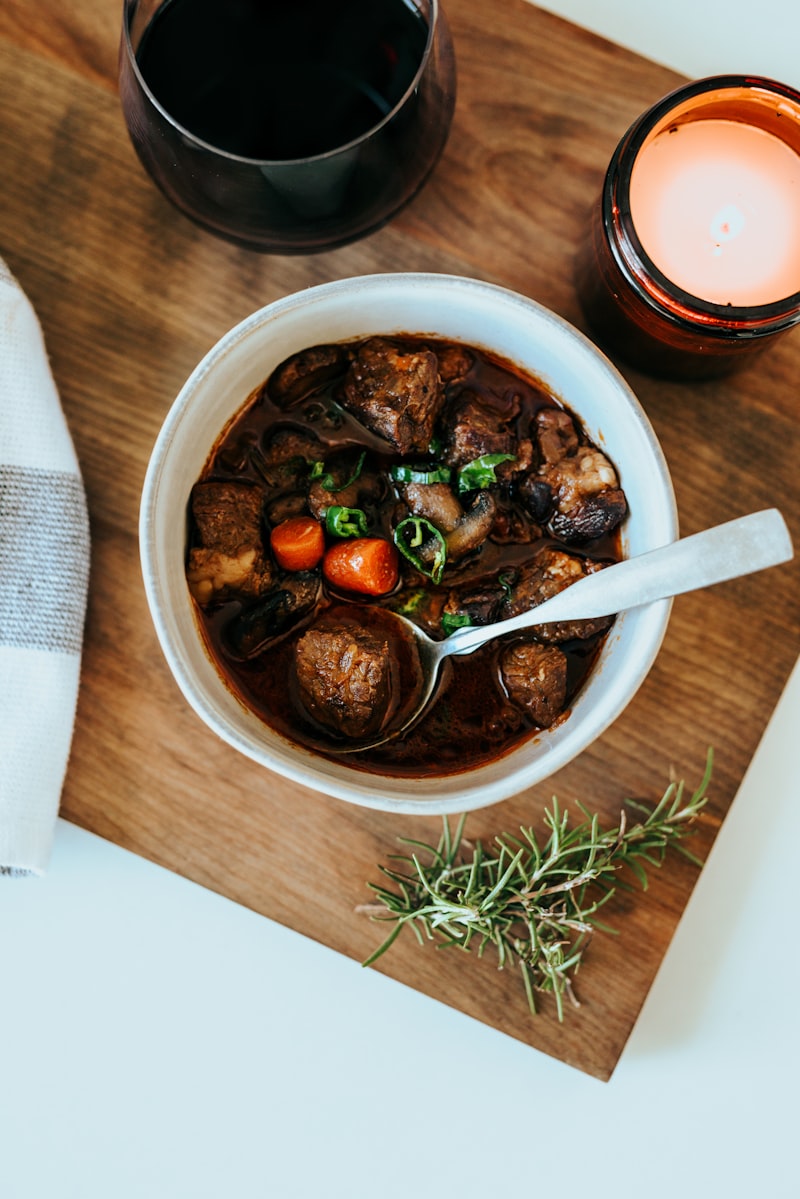 A bowl of beef and vegetable stew with carrots and fresh herbs